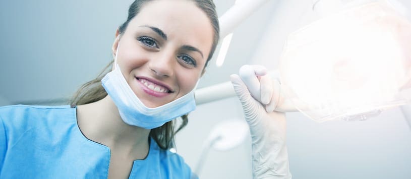 A dental assistant smiling and shining a light at the patient. For a thorough Dental Assisting Program call NWSC.
